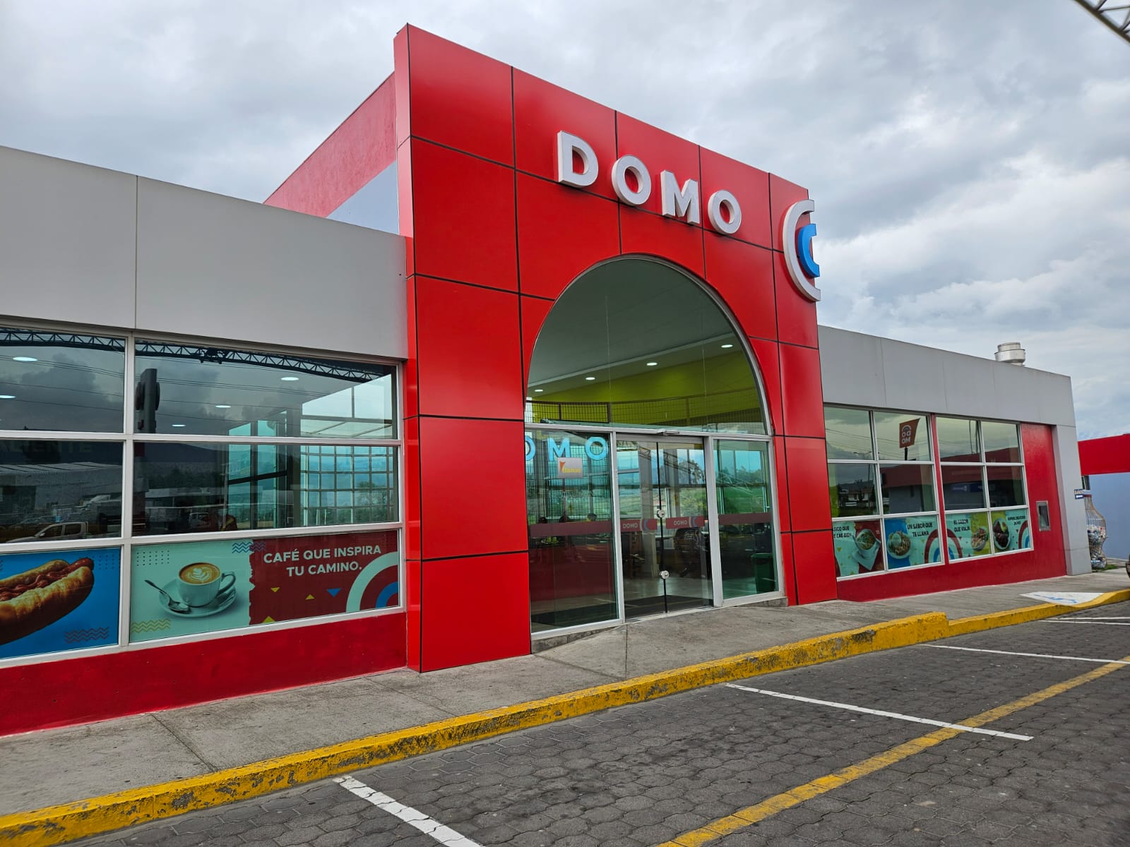 Fachada de DOMO revestida en ACM rojo con arco de entrada y letras corpóreas