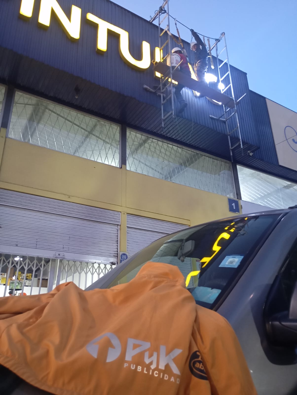 Equipo de PyK instalando las letras iluminadas de Pintulac en una fachada de ACM azul