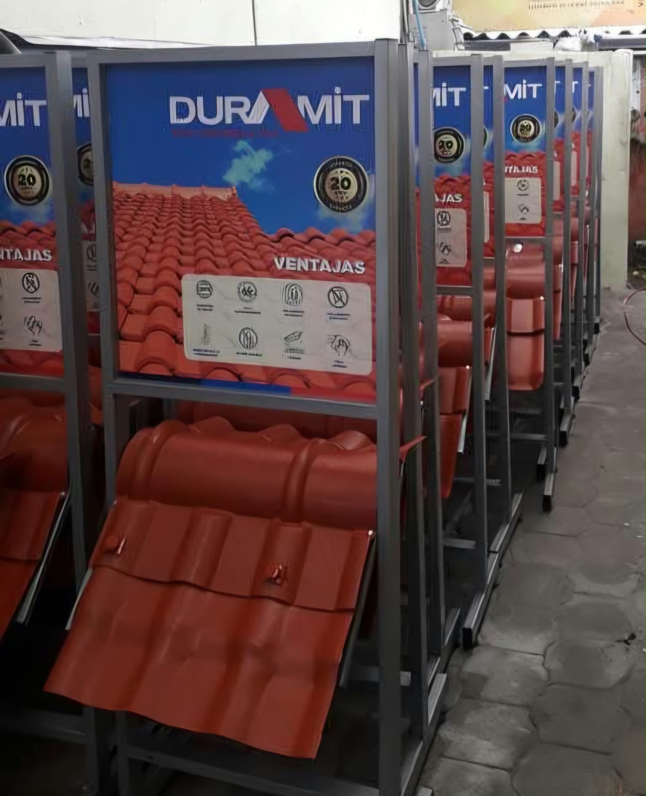 Fila de exhibidores metálicos de tejas Duramit con gráfica de ventajas
