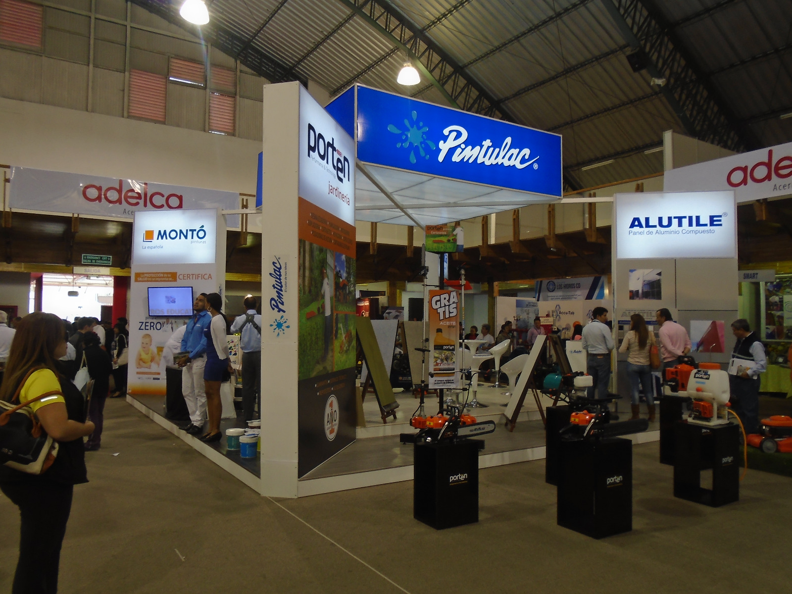 Stand de Pintulac en una feria, con cubo de luz azul, paneles de Porten y Alutile y exhibidores de herramientas