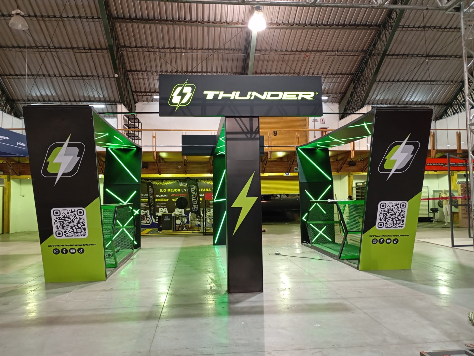 Stand de Thunder Motos en una feria, con luces LED verdes y letrero iluminado