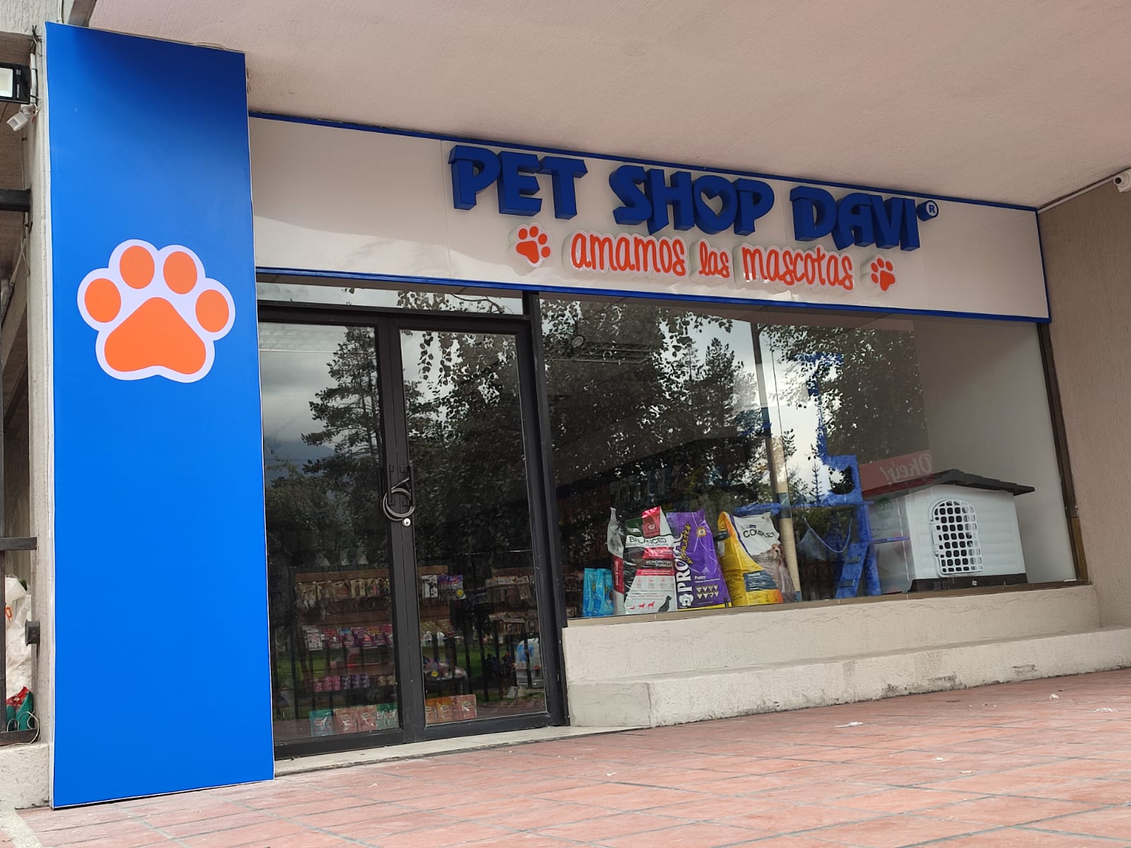 Fachada de Pet Shop Davi con letras corpóreas azules, letrero naranja y columna azul con una huella