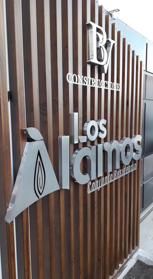 Letras corpóreas en acero inoxidable de Los Álamos y BV Construcciones sobre listones de madera