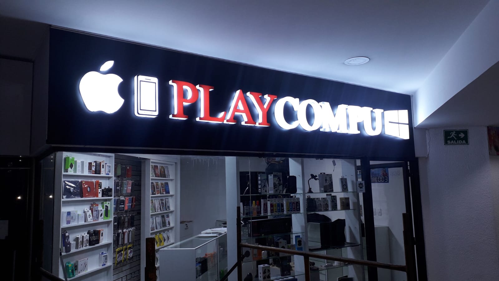 Letrero de Play Compu con letras corpóreas luminosas rojas y blancas sobre fondo negro
