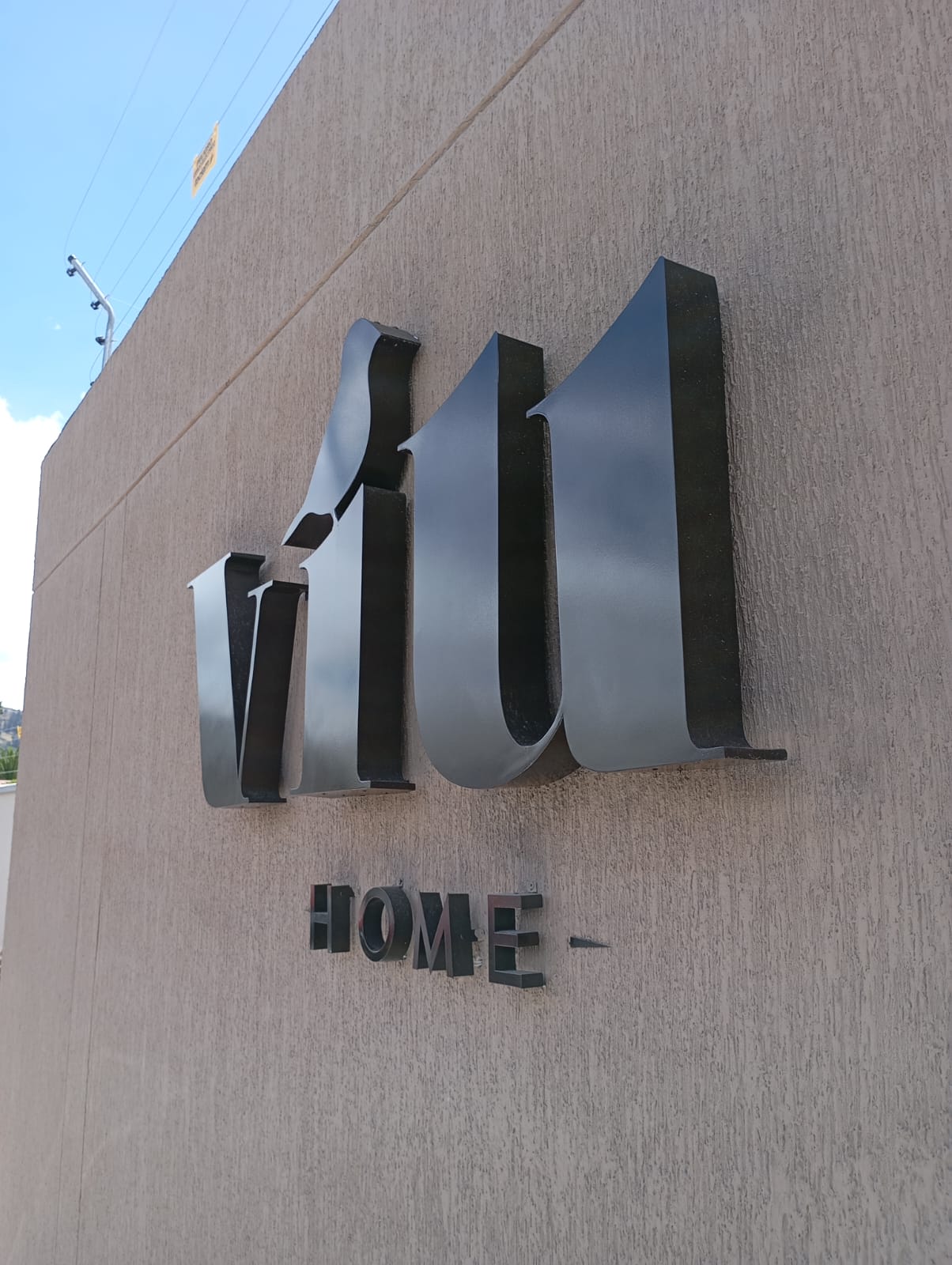 Letras corpóreas negras de vi11 Home en una pared de fachada