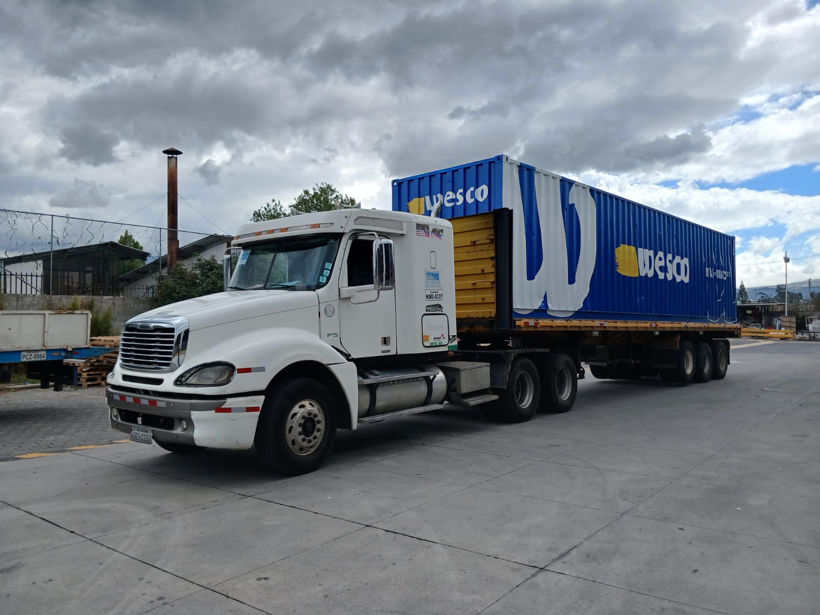 Tráiler con contenedor azul rotulado con la marca Wesco